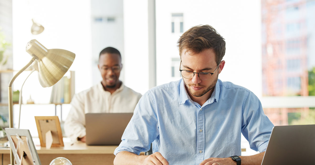 two men working in an office on their computers