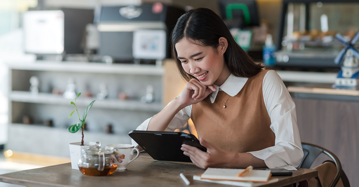 women on using an iPad doing work at a cafe