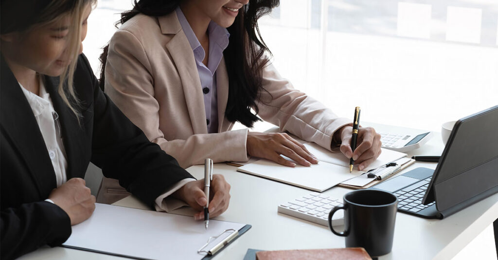 two women writing at their desk