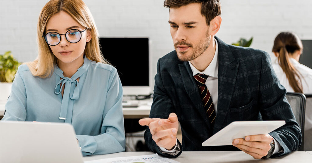 two employees sitting at desk while reviewing a project