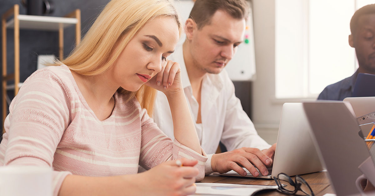 two employees co-working together at the same desk.