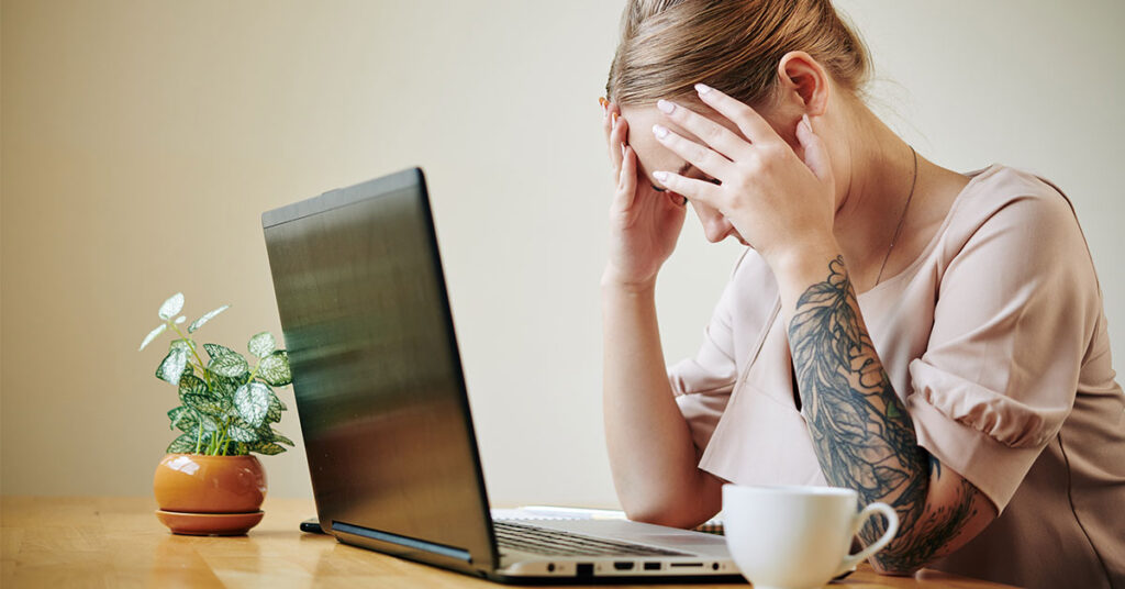 women burnout at work from home with her head in her hands.