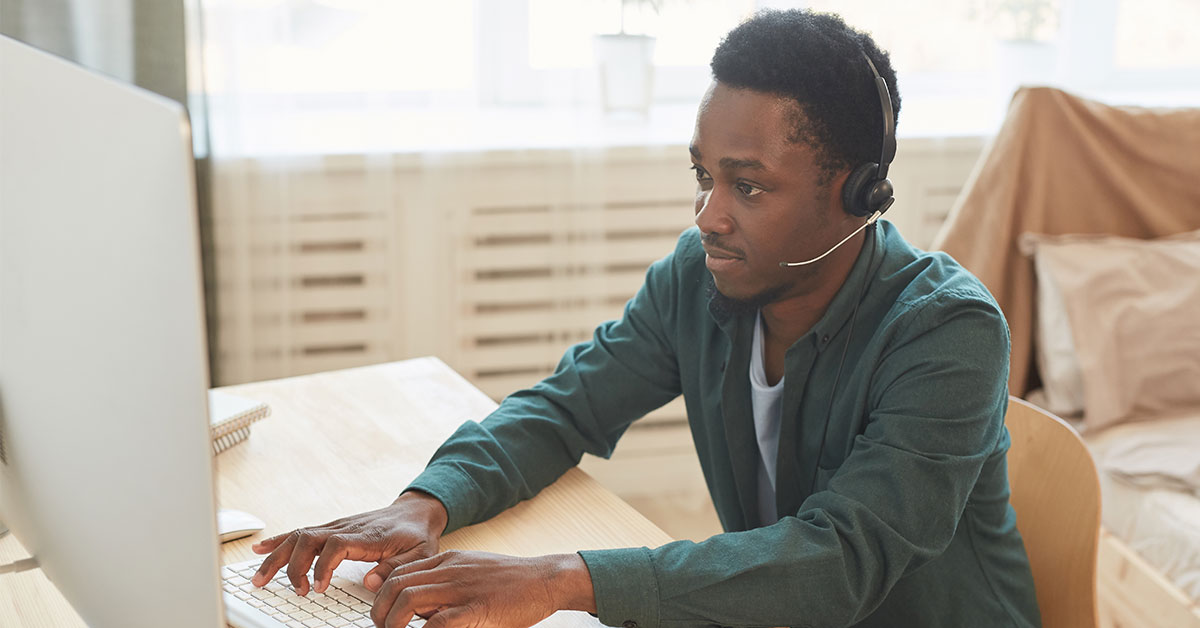 man working from home on his desktop and using a headset to keep in communication.