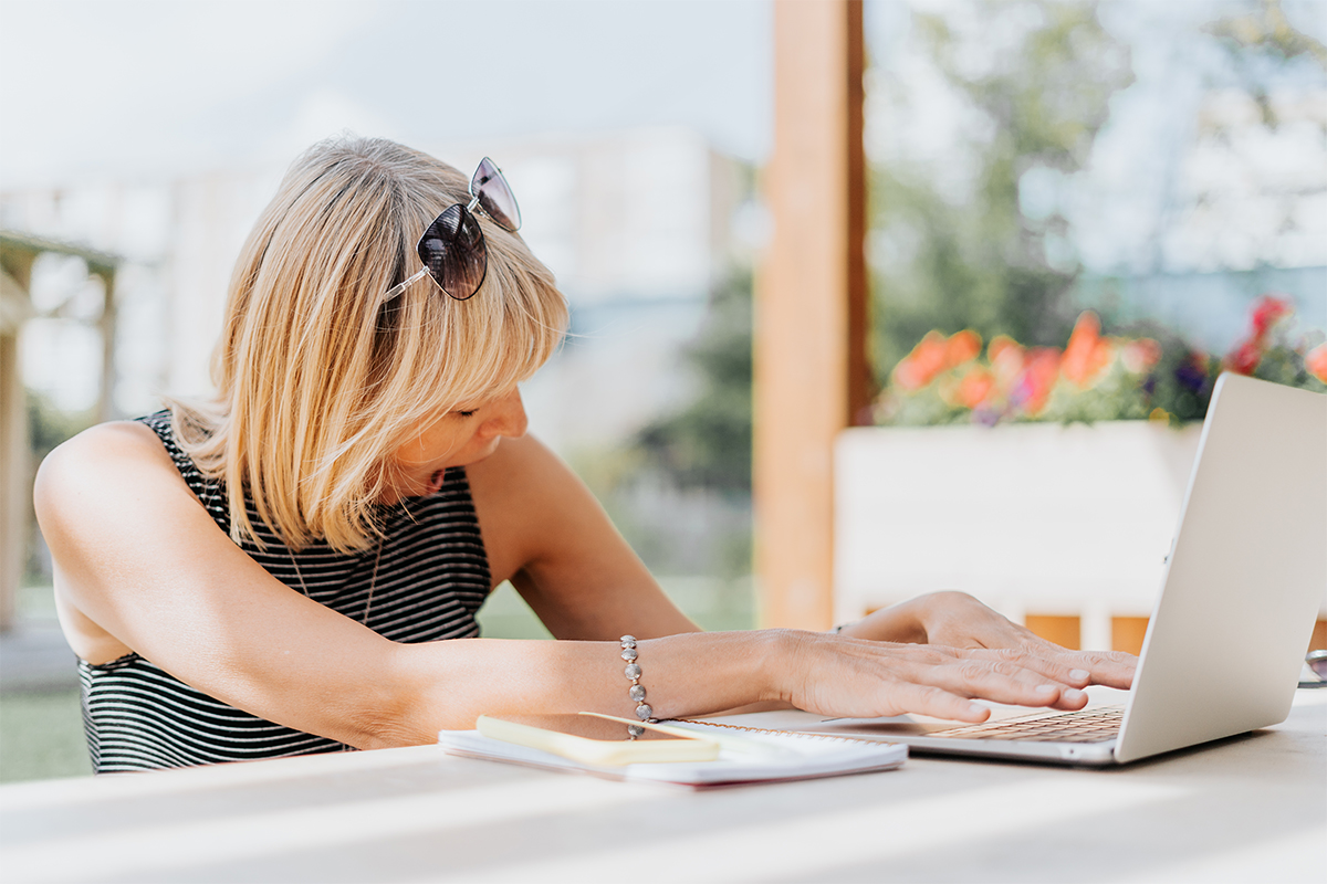 Adult Woman working with laptop and yawn outside in park. Tired senior working and drinking coffee. Using computer. Distance learning online education and online shops.