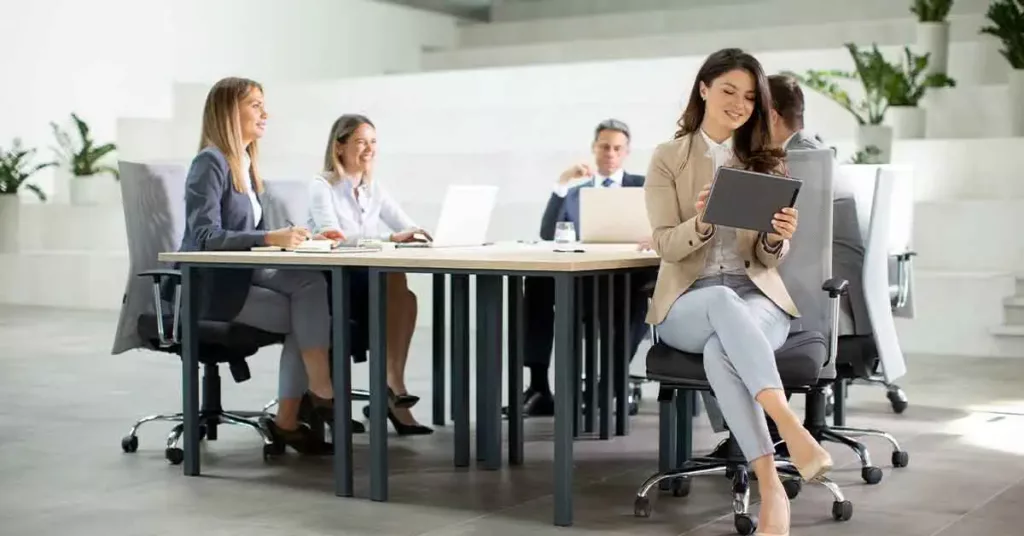 Young woman with digital tablet in the modern office in front of her team